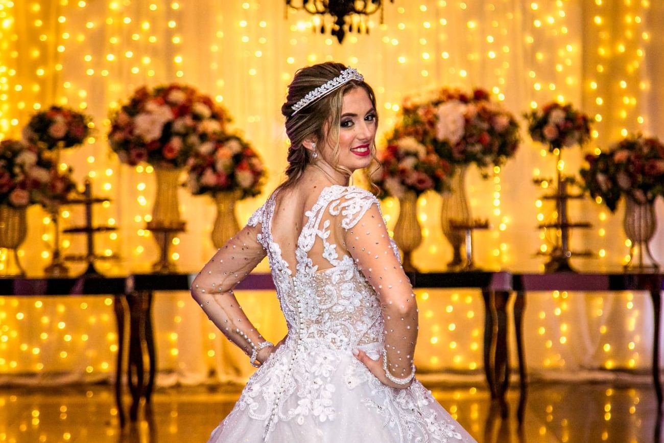 A mesma parede no dia do casamento: cortina de luzes acesa, arranjos e a noiva